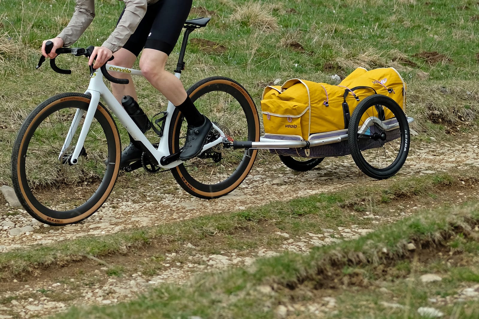 Cyklistický přívěs Veolo 2.0 připojený za kolo na cestě, určený pro cykloturistiku