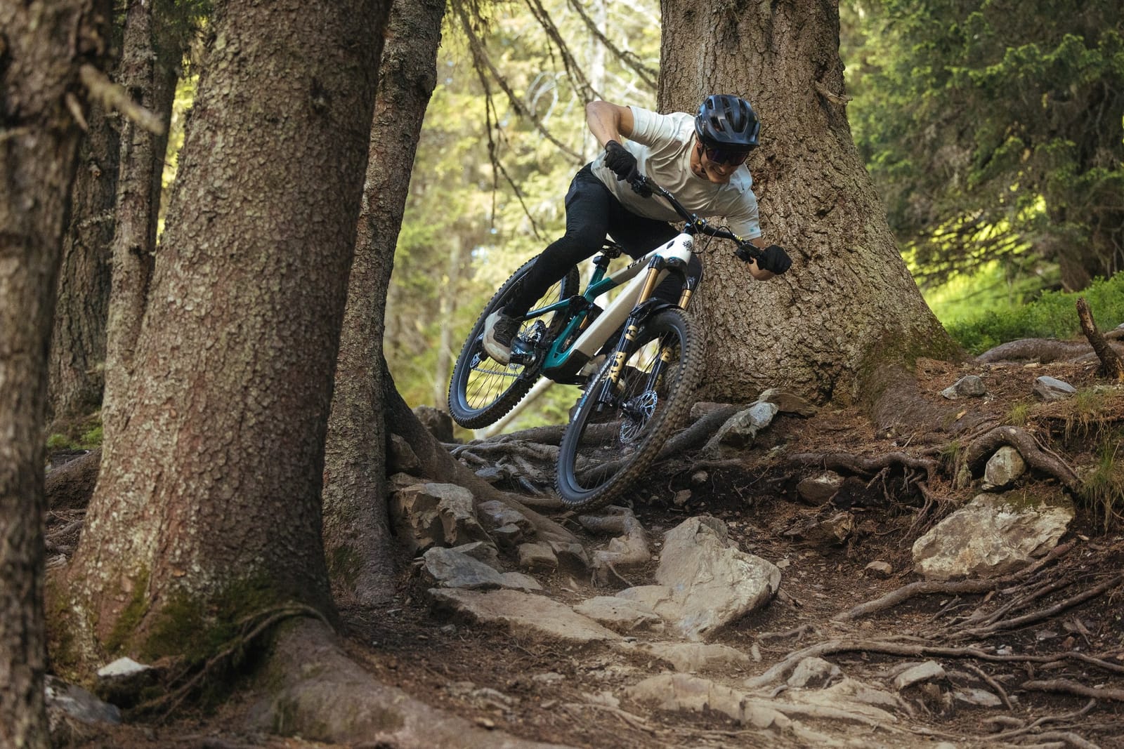 a man riding the Yeti LT down a rocky trail in the forest