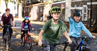 Čtyři cyklisté jedoucí na vyhrazeném cyklistickém pruhu, dva chlapci vpředu a žena s dívkou vzadu